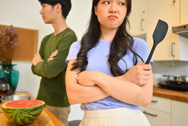 Zdenerwowana młoda kobieta podczas kłótni z mężem w kuchni. Koncepcja małżeńskich problemów i konfliktów. - Zdjęcie, obraz