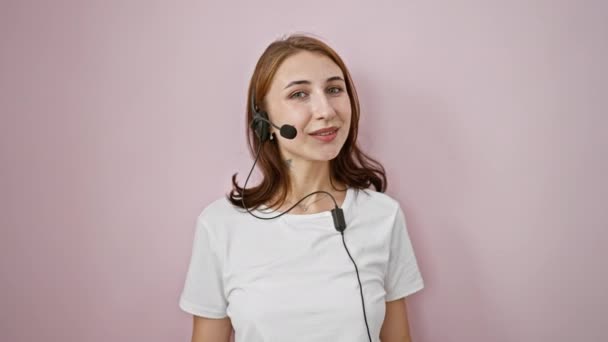 Mujer joven agente del centro de llamadas hablando sobre el fondo rosa aislado - Imágenes, Vídeo