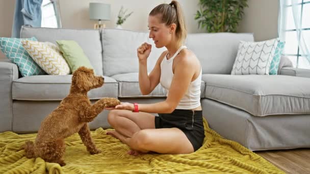 Νεαρή καυκάσια γυναίκα με σκύλο να παίζει καθισμένη στο πάτωμα στο σπίτι - Πλάνα, βίντεο
