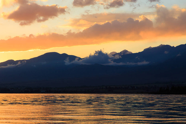 Barevný západ slunce na moři. Horské jezero v paprscích oranžového slunce. Kyrgyzstán, jezero Issyk-Kul. přírodní pozadí - Fotografie, Obrázek