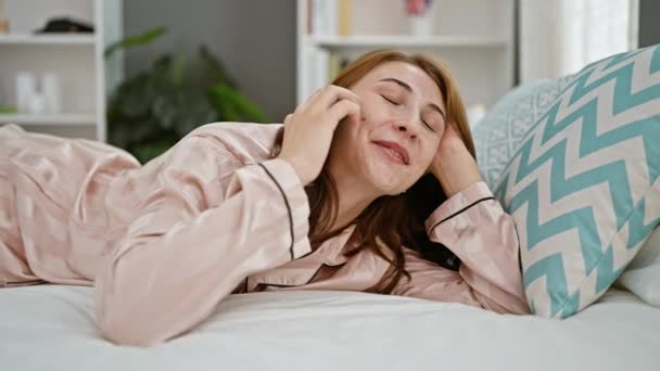 Mladá žena mluví na smartphone ležící na posteli v ložnici - Záběry, video