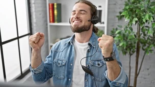 Νέοι Ισπανοί εργαζόμενοι επιχείρηση άνθρωπος χρησιμοποιώντας υπολογιστή και ακουστικά γιορτάζει στο γραφείο - Πλάνα, βίντεο