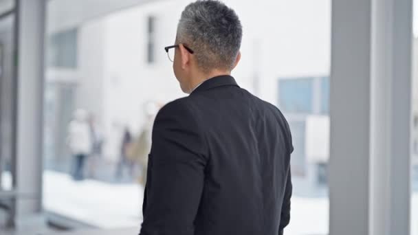 Nuori latino mies liikemies hymyilee luottavainen seisoo kädet ristissä ele toimistossa - Materiaali, video