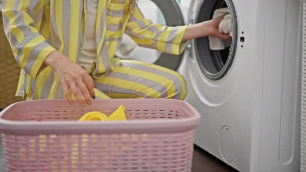 Młoda blondynka myje ubrania w pralni - Materiał filmowy, wideo
