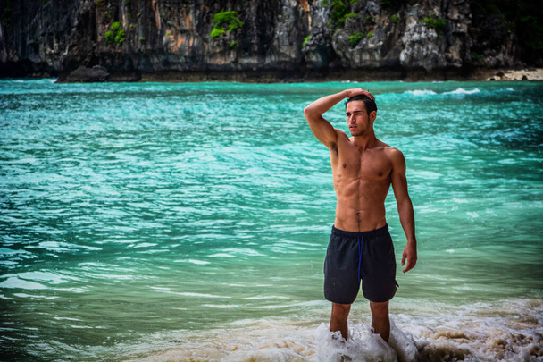 Attractive young man standing on a beach in Phuket Island, Thailand, shirtless wearing boxer shorts, showing muscular fit body - Foto, afbeelding