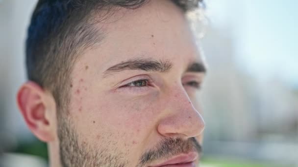 Jonge Spaanse man kijkt naar de zijkant met serieuze uitdrukking op straat - Video