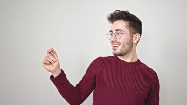 Jonge Spaanse man glimlachend wijzend naar de zijkant over geïsoleerde witte achtergrond - Video