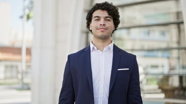 Jeune homme d'affaires latino sourire confiant debout avec les bras croisés geste à la rue - Séquence, vidéo