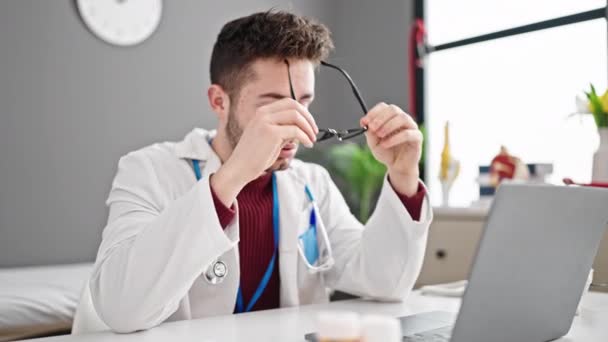 Jovem hispânico homem médico tirando óculos fora estressado na clínica - Filmagem, Vídeo