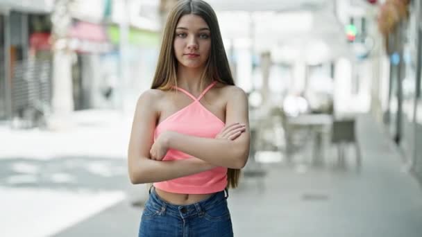 Young beautiful girl standing with serious expression and arms crossed gesture at street - Footage, Video