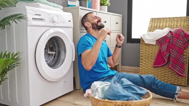 Молодий іспаномовний чоловік чекає на пральну машинку, танцює в пральні - Кадри, відео