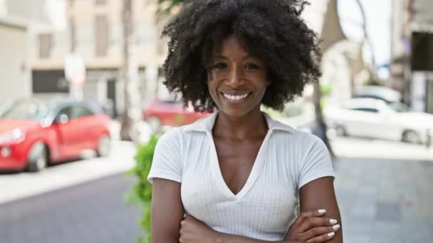 Afro-Amerikalı kadın gülümsüyor. Kollarını kavuşturup caddede duruyor. - Video, Çekim
