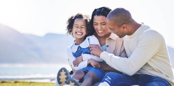 Mother, beach or father laughing with child bonding in Brazil to relax with love, smile or care in summer. Happy family, mom or funny dad with daughter in nature picnic on holiday vacation together. - Photo, Image