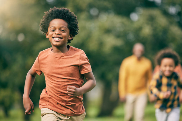 Portrait, running and children at a park with parents, freedom and playing in nature together. Love, energy and excited kid face run in a forest with mother, father and bonding, smile and race games. - Photo, Image