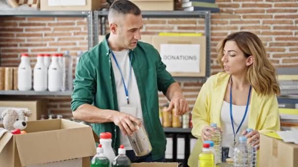 Mies ja nainen vapaaehtoisia laittaa tuotteita paketti lahjoittaa hyväntekeväisyyskeskuksessa - Materiaali, video