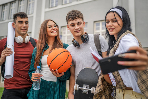 группа подростков фотографируют себя перед школьным университетом мужчины и женщины друзья кавказские мужчины женщины подростки перед кампусом ждать класс обратно в школу концепции - Фото, изображение