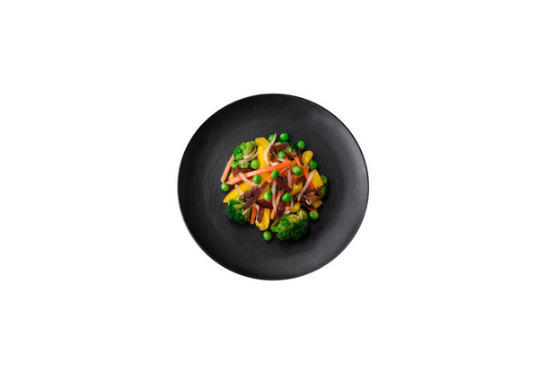 Νόστιμα λαχανικά στον ατμό μπρόκολο, μανιτάρια, μπιζέλια, καρότα και κρεμμύδια σε σκούρο σκυρόδεμα φόντο - Φωτογραφία, εικόνα