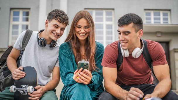 grupa nastolatków gen z przed szkołą uniwersytet używać telefon komórkowy smartfon mężczyzna i kobieta przyjaciele kaukaski mężczyzna i kobieta nastolatki przed kampusem powrót do koncepcji szkoły - Zdjęcie, obraz