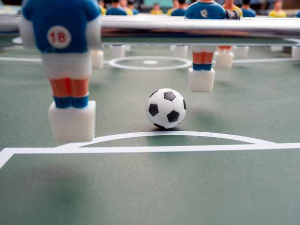 Ένα κοντινό πλάνο κάποιων παικτών και μια μπάλα ποδοσφαίρου σε ένα ποδοσφαιράκι. Επιτραπέζιο ποδόσφαιρο. - Φωτογραφία, εικόνα