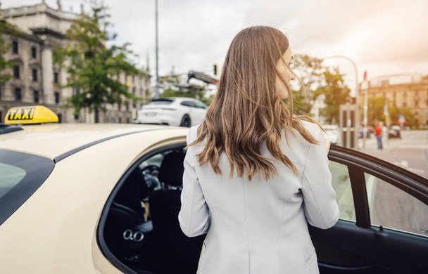 business woman wearing a suit entering a taxi in the city - Photo, Image