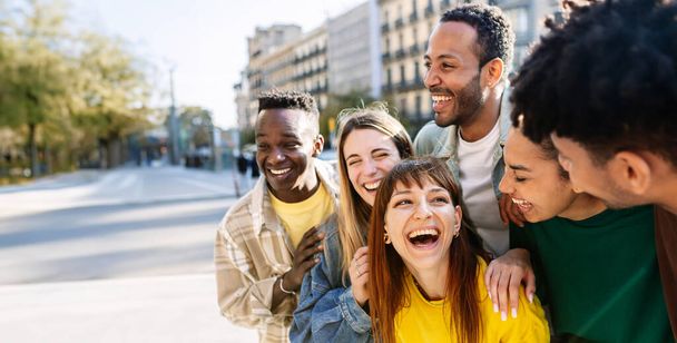 Молодая группа счастливых студентов колледжа веселится вместе на улице. Тысячелетние друзья тусуются, наслаждаясь отпуском на городской улице. Копирование текста. - Фото, изображение
