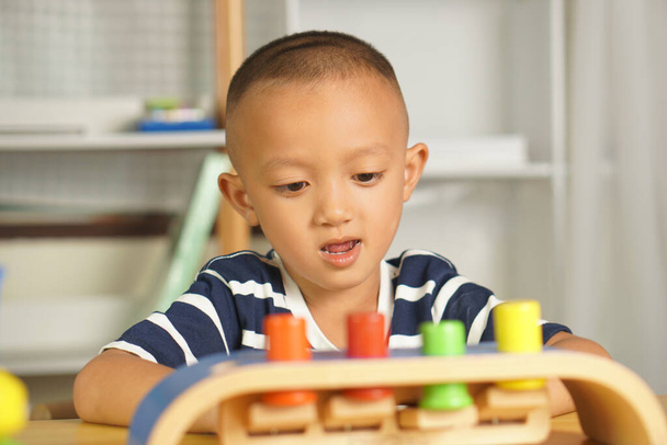 Junge spielt mit Entwicklungsspielzeug auf dem Tisch im Haus. Das Spielzeug ist ein mehrfarbiger Druckknopf. fröhliche Kinder, die Spaß haben - Foto, Bild