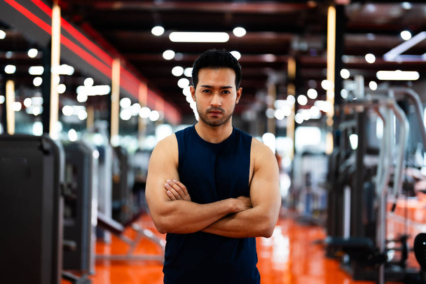 Energetický Fitness Sportsman v tělocvičně. Asijský atlet kříží zbraně. Fešák Chytrý a sebevědomí ve fitness centru - Fotografie, Obrázek