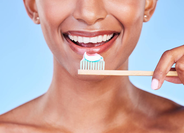 Primo piano, bocca o donna lavarsi i denti in studio per cure dentistiche, respiro fresco o sorriso sano su sfondo blu. Faccia di modello felice, spazzolino di bambù ecologico e dentifricio di pulizia orale. - Foto, immagini