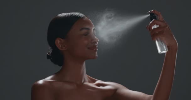 Skincare, arc köd és nő a stúdióban kozmetikai, szépség és arckezelés ragyogás. Bőrgyógyászat, tiszta és indiai női modell szürke háttérrel izolált természetes egészségügyi spray termékkel - Felvétel, videó