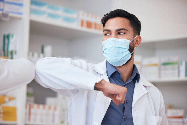 Man, elbow greeting and pharmacist with healthcare, social distancing or covid regulations. Person, medical professional or employee with protection, mask or greet with pandemic policy in a workplace. - Photo, Image
