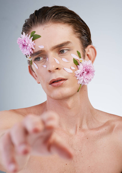 Touch, skincare and flowers on face of man in studio for beauty, natural cosmetics and creative. Glow, idea and floral art with model on white background for makeup, spa treatment and wellness. - Fotografie, Obrázek