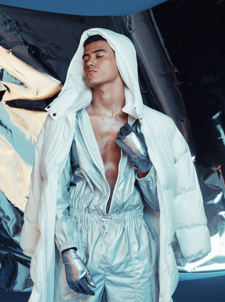 Fashion, future and cyberpunk with a model in a silver outfit for a magazine photo shoot in studio. Art, holographic and sci fi with a young man posing for creative, vaporwave or trendy style. - Photo, Image