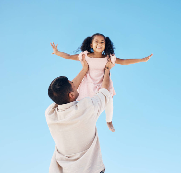 Portret, blauwe lucht en een kind met papa voor het spelen, het heffen van vrijheid en samen in de zomer. Plezier, familie en een meisje kind met een vader vasthouden voor vliegen, liefde en binding op een vakantie als gelukkige mensen. - Foto, afbeelding