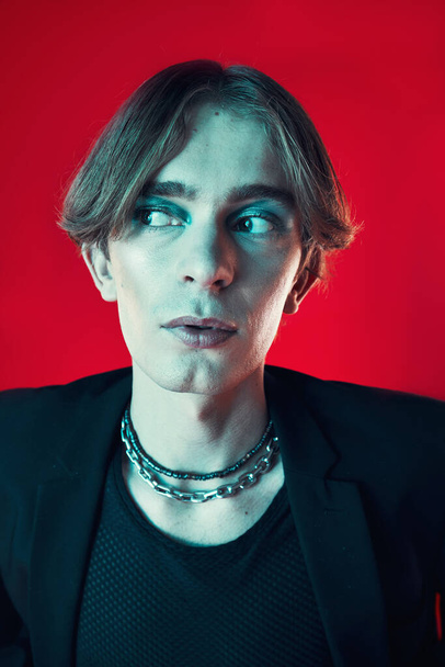 Fashion, thinking and gay man in makeup at studio isolated on a red background. Cosmetics, lgbtq style and male model in cool clothes, aesthetic and serious idea for queer or non binary. - Фото, зображення