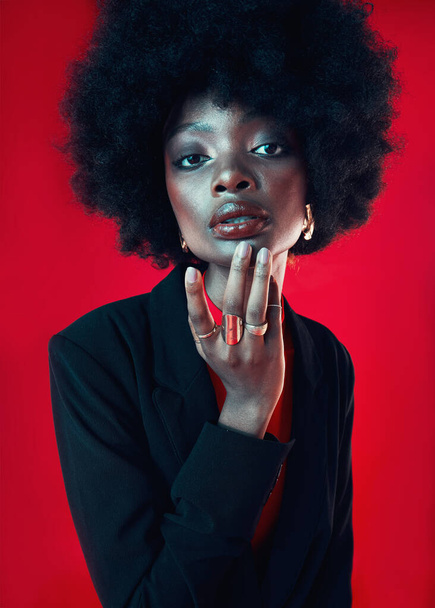 Black woman, portrait and afro, hair and beauty with makeup and shine isolated on red background. Hairstyle, haircare and texture with growth, face skin glow and confident African model in a studio. - Foto, imagen