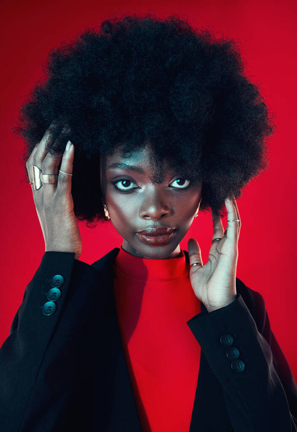 Black woman, makeup and afro, hair and beauty in portrait with shine isolated on red background. Hairstyle, haircare and texture with growth, skin glow on face and confident African model in a studio. - Fotó, kép