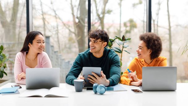 Ευτυχισμένη ποικιλόμορφη τρεις μαθητές χρησιμοποιώντας διάφορα gadgets και κουβέντα, κάθεται στο πανεπιστημιακό κοινό, μάθηση για τις εξετάσεις, τύπος και κυρίες που κάνουν online έρευνα, πανόραμα - Φωτογραφία, εικόνα