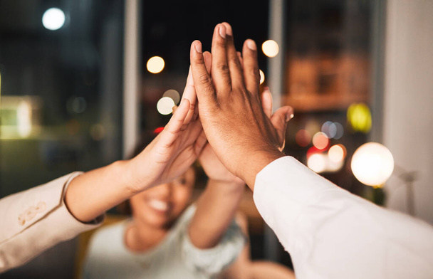 Succes, close-up en zakenmensen met een high five 's nachts voor motivatie of teambuilding. Gelukkig, donker en medewerkers met een gebaar in een kantoor voor doelen, doel of realisatie op een deadline. - Foto, afbeelding