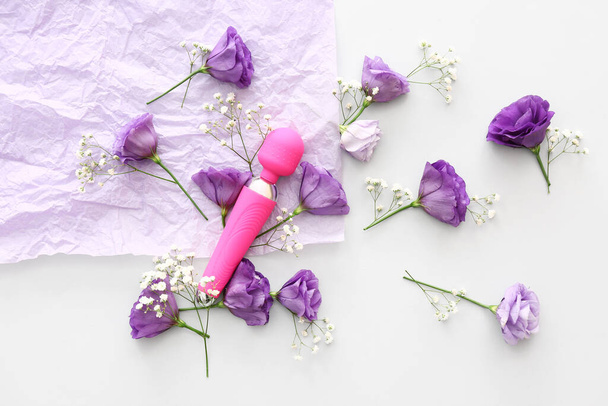Composition with beautiful flowers and vibrator on white background - Photo, Image