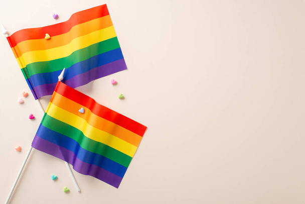 Vista superior plana laico foto de composición LGBT con dos banderas de arco iris y corazones decorativos sobre fondo beige con espacio para el texto - Foto, Imagen
