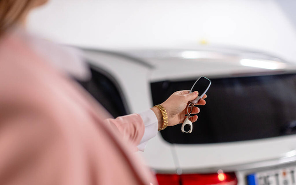 donna utilizzando un fob come chiave per aprire la sua auto della classe media superiore in garage - Foto, immagini