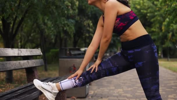 Aziatische vrouw stretching benen in de zomer park op bank.  - Video