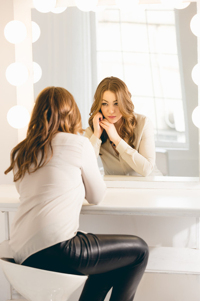 stijlvolle vrouw op zoek in haar reflectie op de spiegel met bollen - Foto, afbeelding
