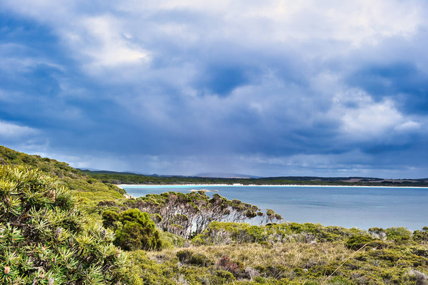 Romlatlan tengerparti táj a Two Peoples Bay Nature Reserve-ben, Albany közelében, Nyugat-Ausztráliában. A távolban a hosszú strand mentén az öböl. Sötét felhők. - Fotó, kép
