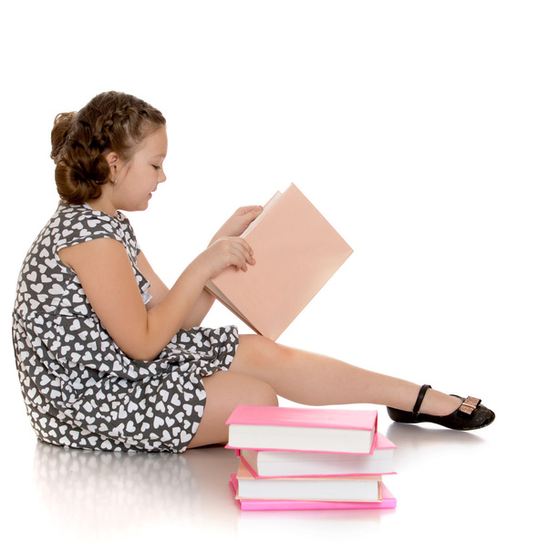 intelligentes Schulmädchen liest ein Buch sitzend auf dem Fußboden - Foto, Bild
