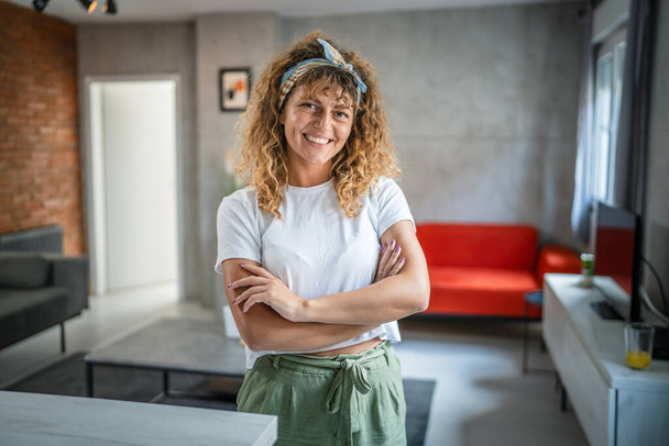 Close up portrait of one adult woman with curly hair happy smile positive emotion copy space standing at home indoor - Foto, afbeelding