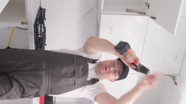Безумно веселый монтажник кухонной мебели танцует с рабочими инструментами. Счастливый работник на работе. Вертикальное видео - Кадры, видео