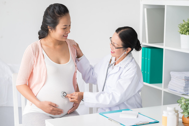 Лікар слухає живіт вагітної жінки
 - Фото, зображення