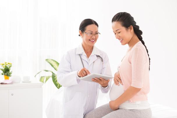 Doctor using  tablet  with pregnant woman - Fotó, kép