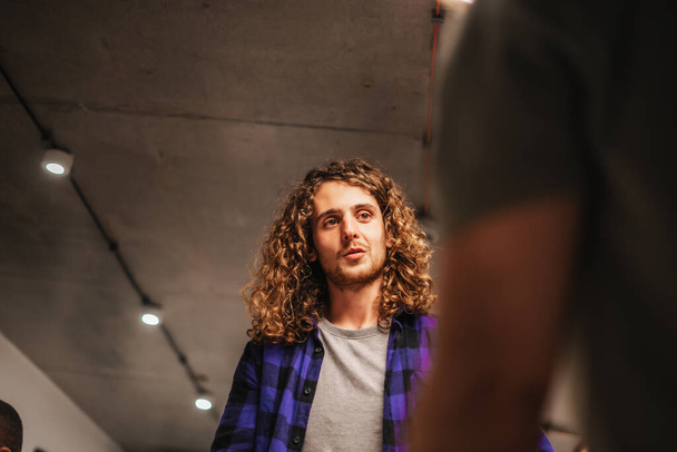 Male employee with long curly hair discussing at work with his colleagues - Photo, Image